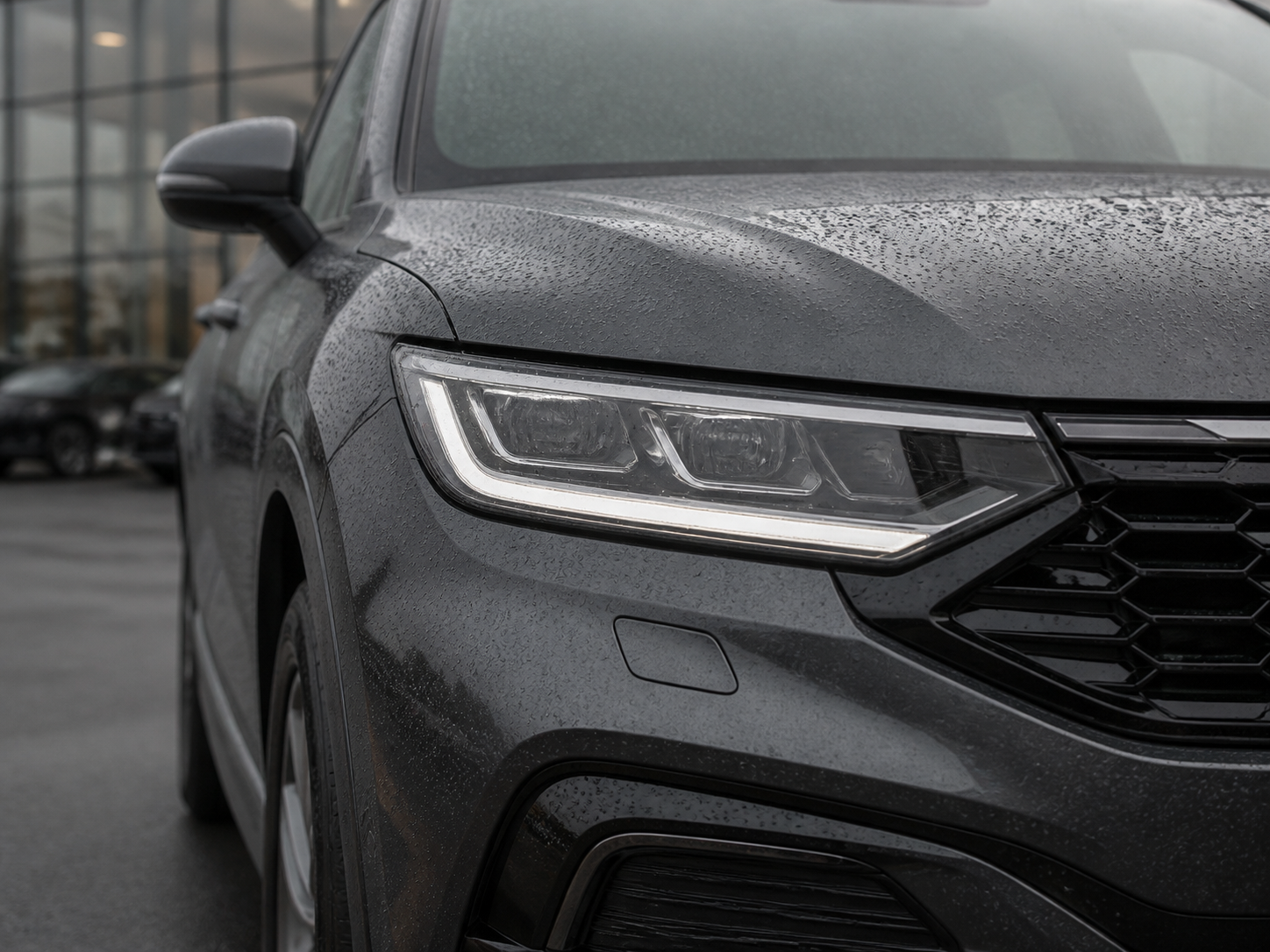 Rain droplets on the headlamp and bodywork of a modern vehicle