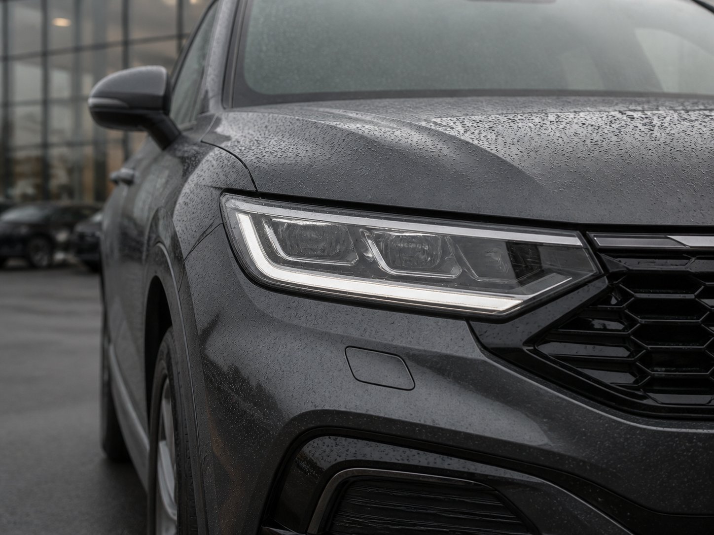 Rain droplets on the headlamp and bodywork of a modern vehicle